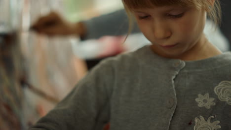 focused girl mixing paints on jar