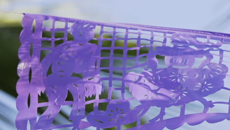 primer plano de perforaciones en papel picado púrpura mientras sopla suavemente en el viento