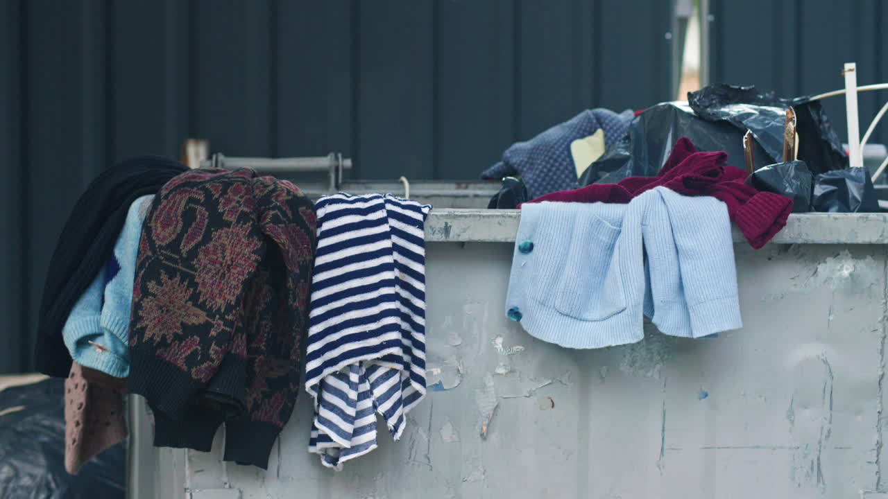 Abandoned clothes over, near and inside a dumpster in Sofia, Bulgaria