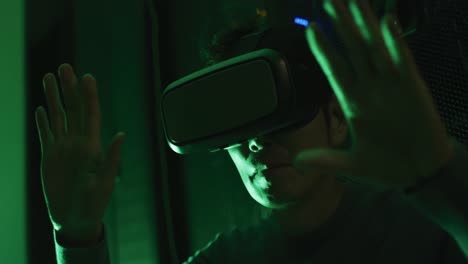 Close-up-of-asian-man-wearing-vr-headset-by-computer-servers