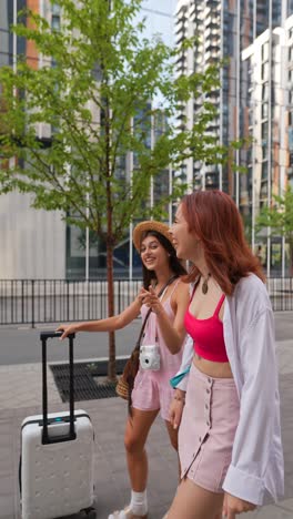 two women walking with luggage in a city