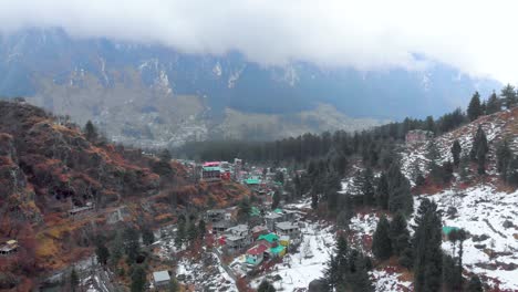 Tiro-Aéreo-Hacia-Atrás-De-La-Ciudad-Vieja-De-Manali-Después-De-La-Nevada-Cerca-Del-Frente-Del-Río-Manalsu-En-Himachal-Pradesh-Tiro-Con-Un-Dron-En-4k