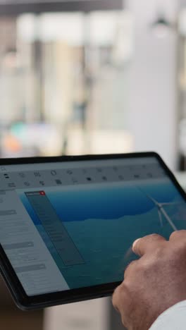 Close up of engineer in office using tablet to work on wind turbine CAD design
