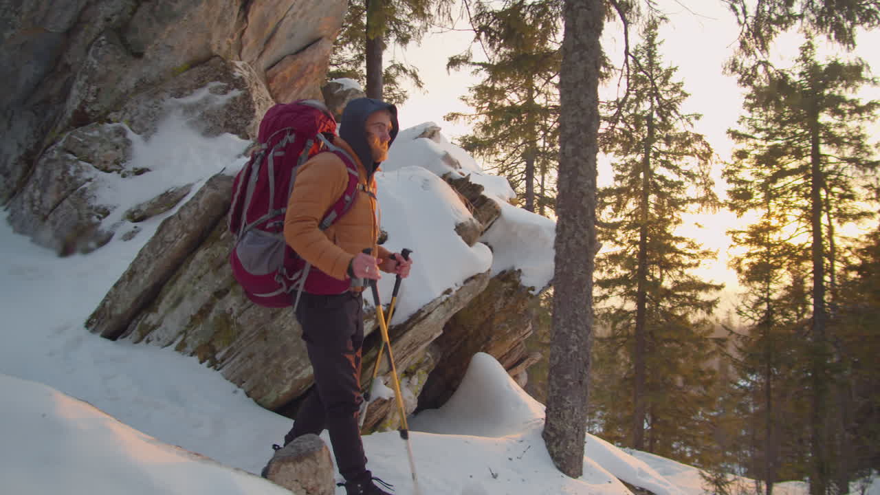 Hiker Walking Downhill in Snowy Mountains at Sunset