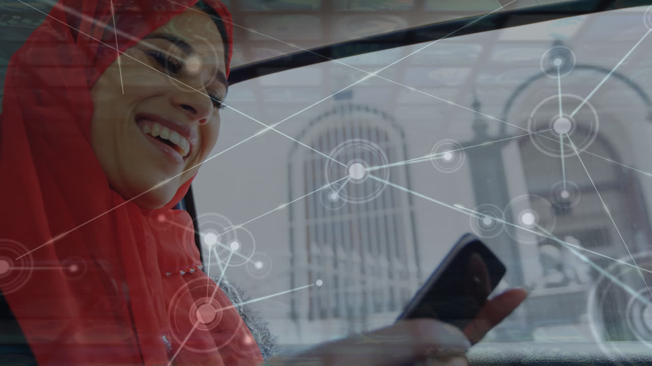 Animazione di punti che si collegano con linee su una giovane donna sorridente con hijab che usa il cellulare in auto