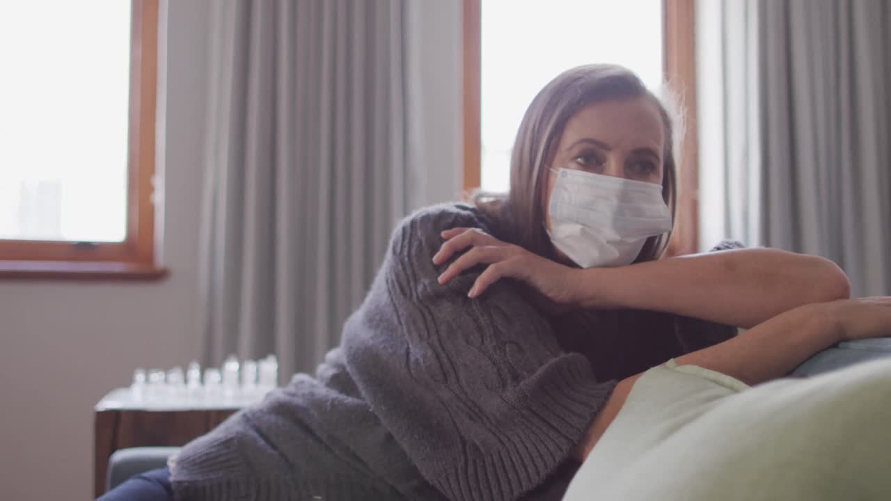 mujer con máscara facial acostada en el sofá en casa