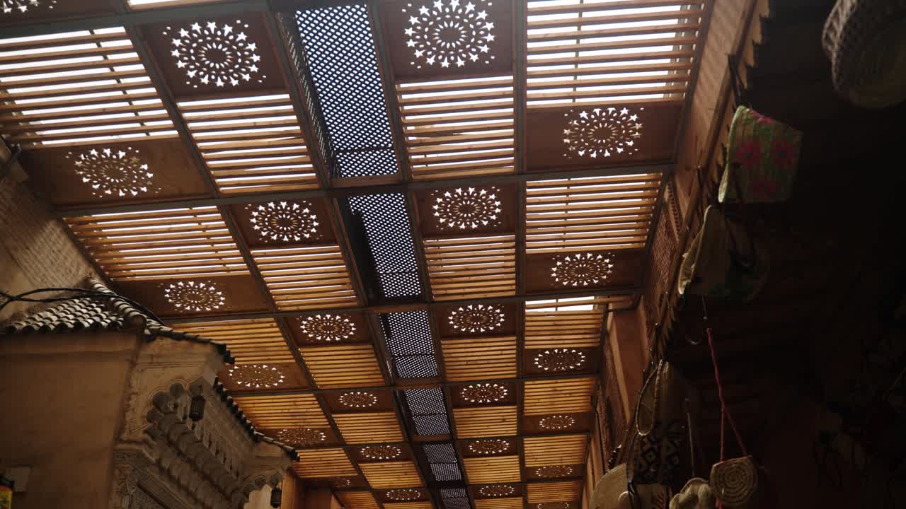Wooden lattice roof with geometric cutout panels inside Marrakech Medina souk