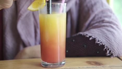 woman drinking a layered cocktail at a cafe