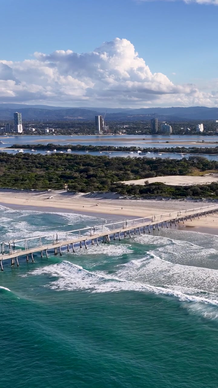 Højvinkel luftfoto af bølger, der slår mod The Spit Mole i Main Beach, Australien.