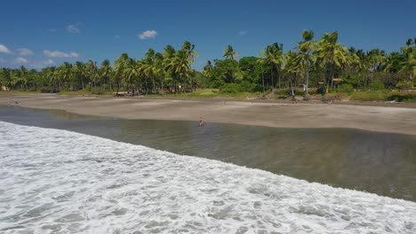 Mujer-Haciendo-Yoga-En-Una-Hermosa-Playa-En-Un-Lugar-Soleado