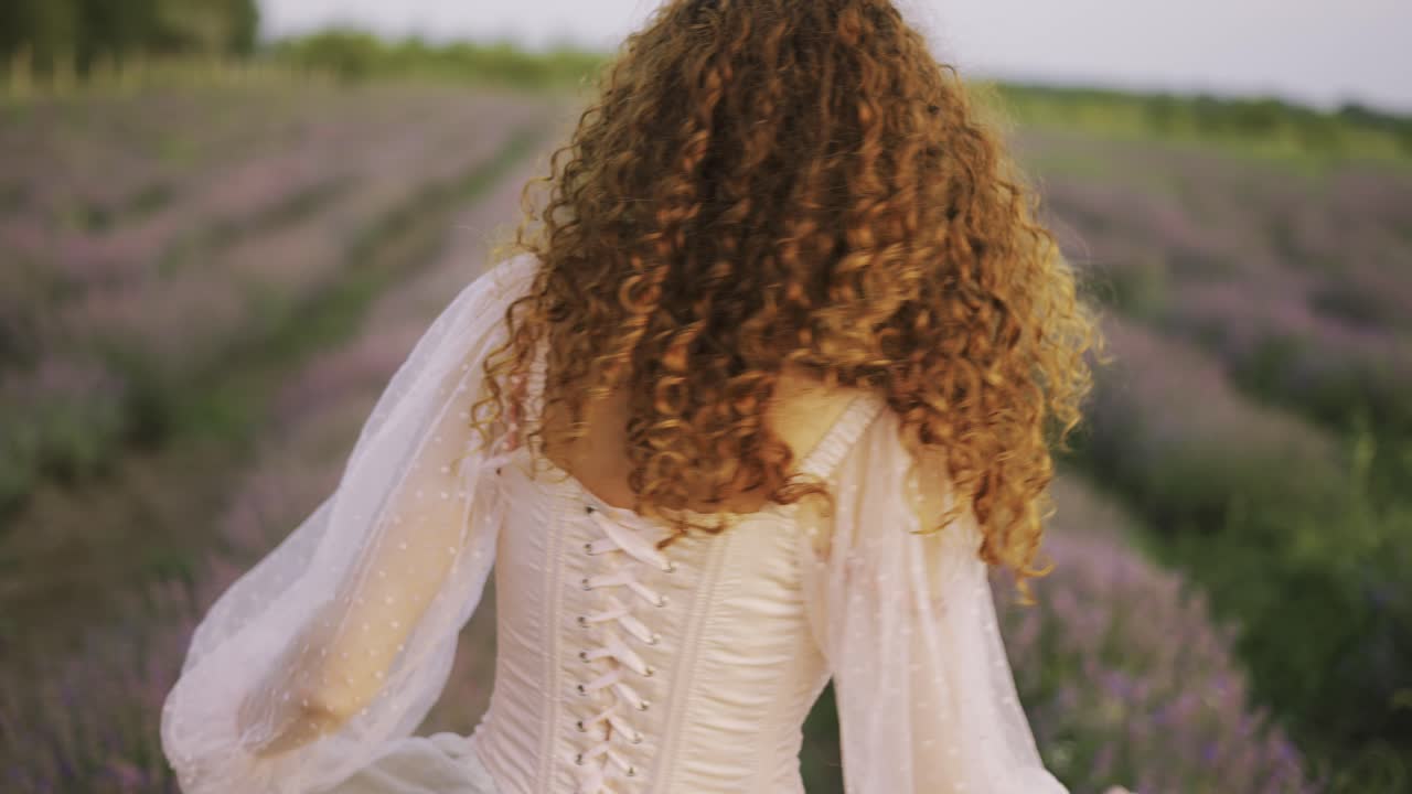 분홍색 드레스를 입은 아름다운  ⁇ 은 소녀는 해가 지는 여름에 라벤더  ⁇ 에서 회전합니다.