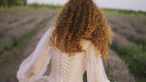 hermosa niña delgada en vestido rosa gira en el campo de lavanda en verano al atardecer