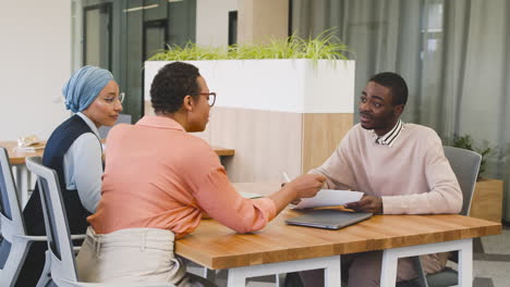 man asks a question about a document to a businesswoman in a job interview