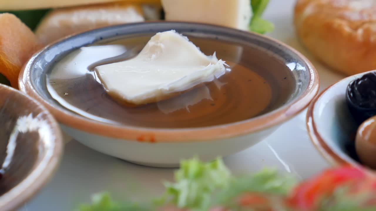 Breakfast with cheese, butter, jam, honey, tomato, salad, bread, olives, and apricot