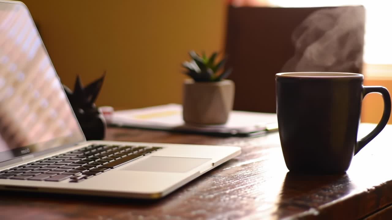 A Cozy Workspace Scene Featuring a Laptop and a Steaming Mug of Coffee, Perfect for Productivity and Relaxation in a Comfortable Home Office Environment