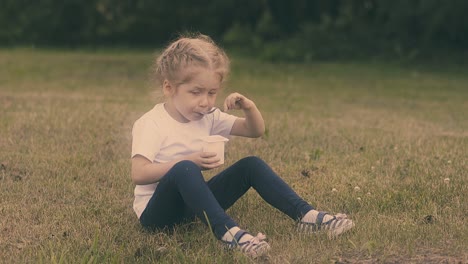 small concentrated girl eats yogurt with silver metal spoon