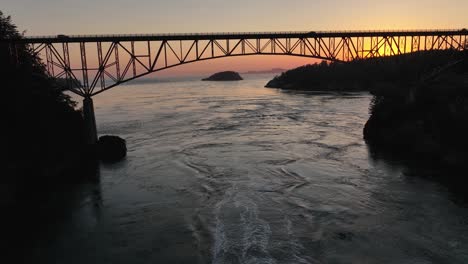 Vista-Aérea-Moviéndose-Sobre-Un-Bote-Corriendo-Bajo-El-Puente-De-Paso-De-Engaño-Y-Luego-Pasando-Sobre-La-Parte-Superior-Del-Puente