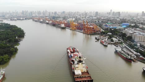 aerial view over container carrier ship cruising along chao phraya river heading to port of bangkok, thailand.