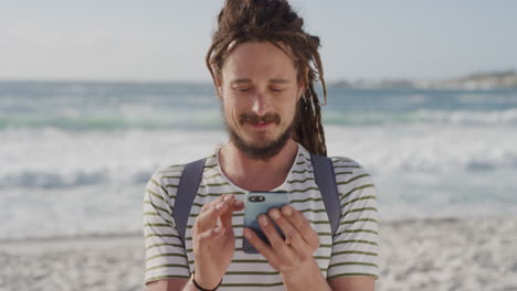 Joven-Turista-Usando-Teléfonos-Inteligentes-Enviando-Mensajes-De-Texto-Navegando-Comunicación-Móvil-Compartiendo-Aventuras-De-Vacaciones-En-La-Playa-En-Línea-Disfrutando-De-Las-Vacaciones-De-Verano-En-La-Soleada-Playa