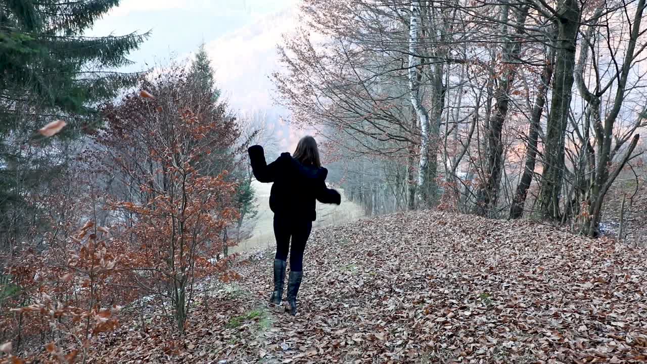 한 젊은 여성이 행복하게 달리고 나무와 강을 향해 단풍에 뛰어든다
