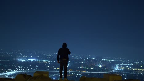 Man-in-Black-Jacket-Standing-on-a-top-view-overlooking-the-expressway-at-midnight-thinking-with-cigarettes