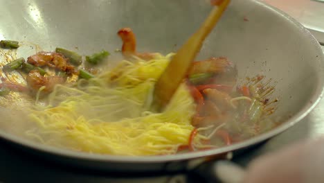 CU-Slow-motion-Cook-prepares-pasta-in-frying-pan-in-oil-with-fresh-vegetables