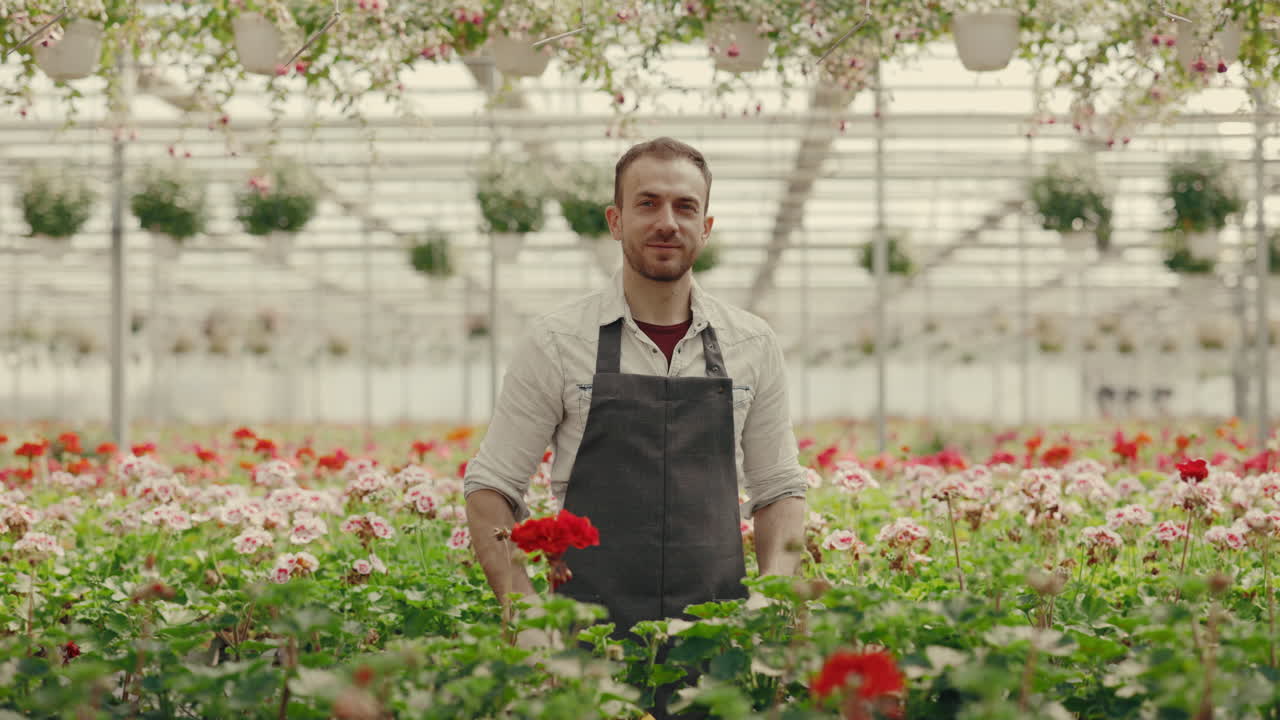 Giardiniere che lavora con un tablet in una serra piena di fiori.