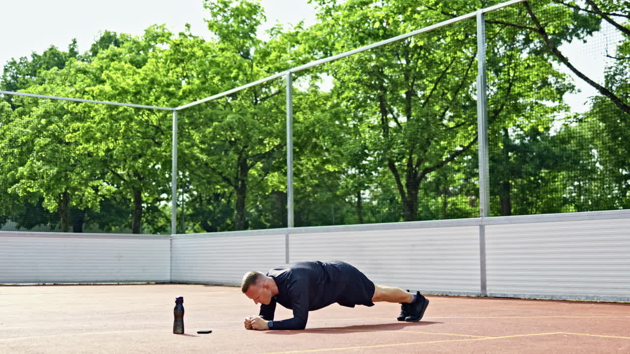 Athletic man in sneakers and shorts doing sports outdoors. Man doing training on sports ground in park. Sports lifestyle. Men's clothing for sports