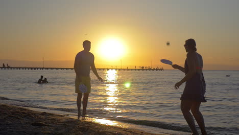 pareja jugando a la pelota de raqueta al atardecer