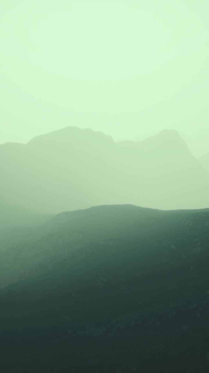 Dusk settles over the rugged mountain landscape shrouded in mist