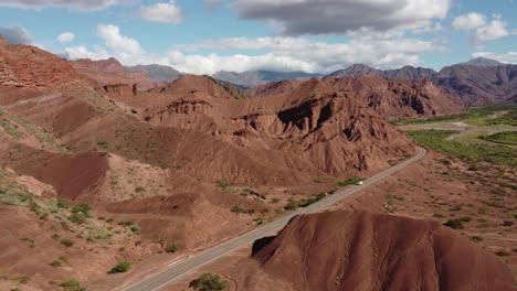 Aerial:-White-truck-drives-highway-through-eroded-red-rock-landscape