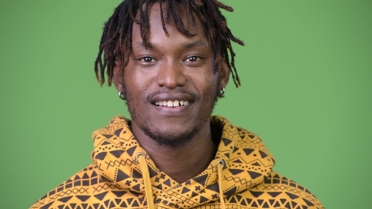 Giovane uomo africano felice su sfondo verde