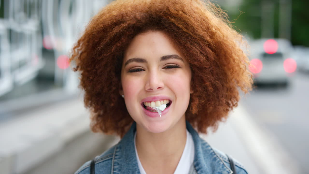 Ritratto di una ragazza audace con capelli afro che soffia una bolla