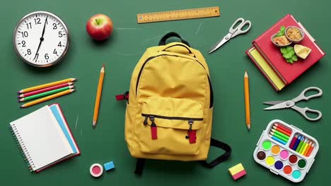 top view flat lay of school supplies and a yellow backpack