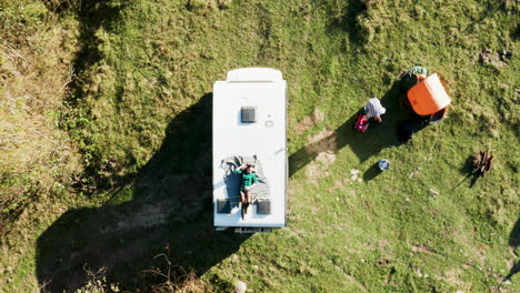 top view of beautiful young woman relaxing on top of retro camper van