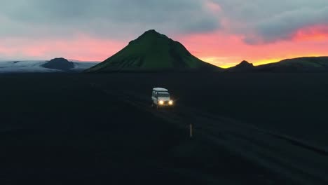aerial drone footage spinning around a white 4x4 truck vehicle car parked on a rural and desolate muddy road in the mountains during sunset or sunrise at greenland or iceland nature landscape.