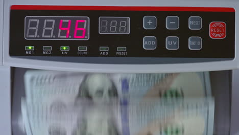 control panel of cash counting machine. us dollars being counted in the device. close up.