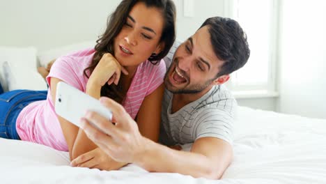 pareja tomando una selfie desde el teléfono móvil en el dormitorio