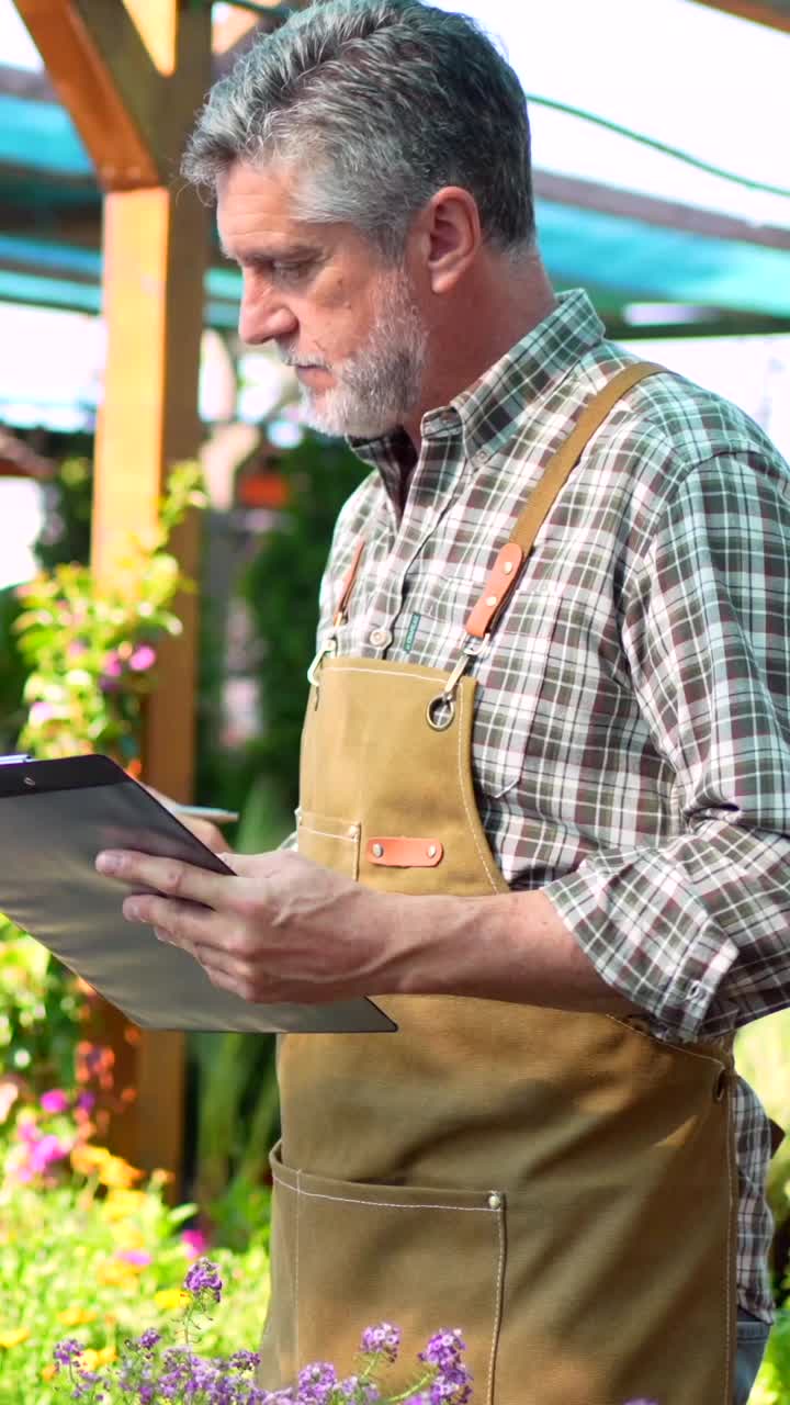 Gardener Inspecting Flowers in a Nursery