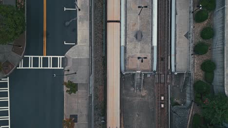 aerial top down shot of train riding on rail in city of atlanta with cars in road during cloudy day
