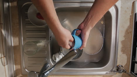 vista superior de un hombre lava los platos sucios en su cocina
