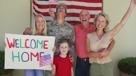 Porträt-Eines-Kaukasischen-Männlichen-Soldaten,-Der-Seine-Lächelnde-Familie-über-Der-Amerikanischen-Flagge-Umarmt