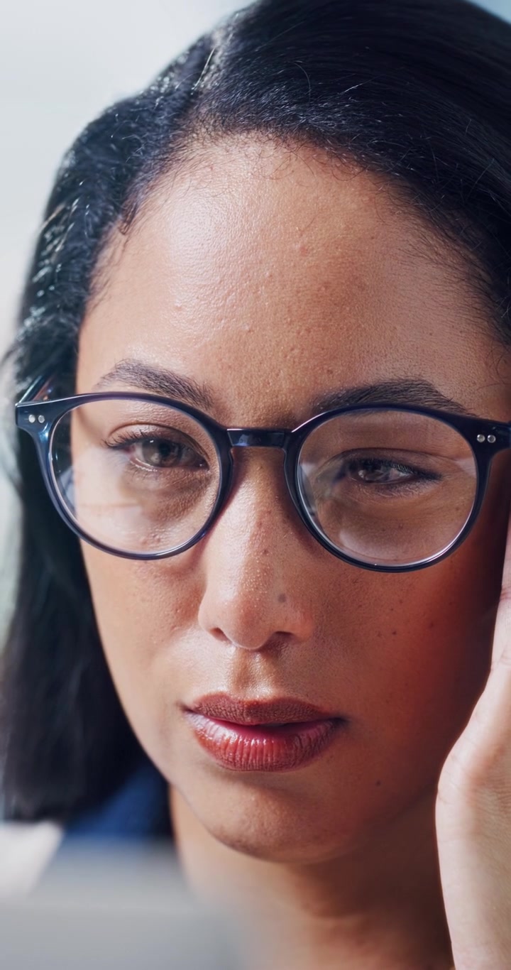 Primo piano di una donna concentrata con gli occhiali che lavora al computer
