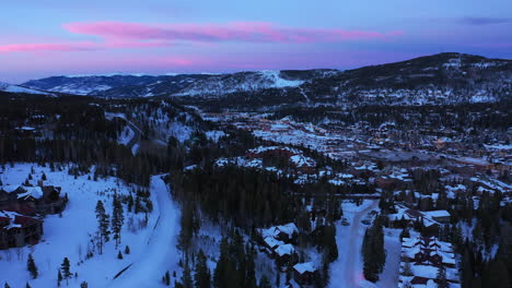 Schweben-Sie-Aus-Der-Luft-über-Eine-Malerische,-Schneebedeckte-Weihnachtsstadt,-Eingebettet-In-Die-Berge-Mit-Immergrünen-Bäumen-Und-Rosa-Und-Blauem-Himmel