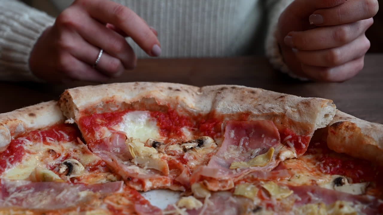 Close up of a woman eating a slice of pizza at a restaurant