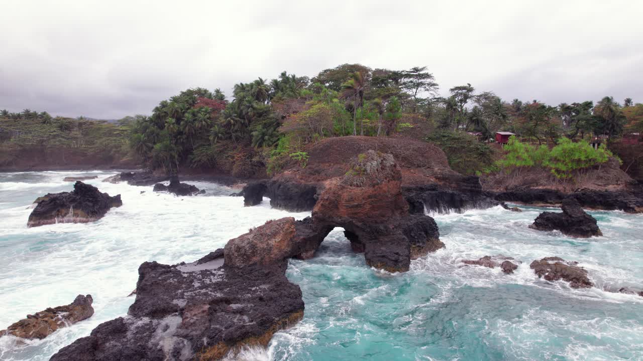 Stormy waves crash on Praia Piscina, São Tomé, a dramatic blend of wild ocean power and serene tropical beach landscape