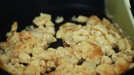 a time lapse close up shot, turning over the omlet on a black hot pan and scrumbling the eggs, making a breakfast 4k video