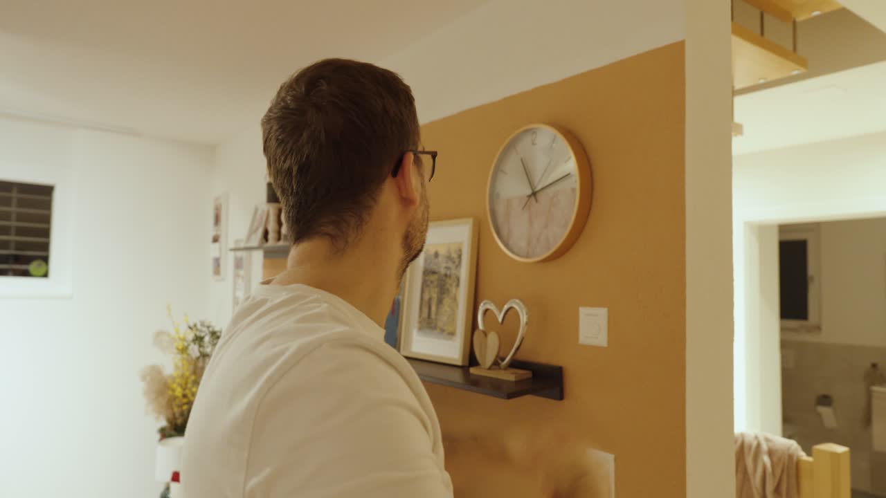 Un uomo guarda pensieroso un orologio sulla parete, a simboleggiare la lentezza del tempo, la noia o la sensazione che il tempo non passi mai.