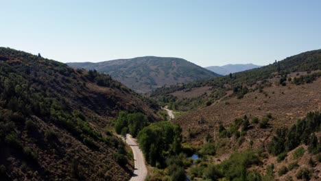 beautiful rising aerial drone wide shot of a long windy canyon road in spanish fork canyon from a camping spot in utah on a warm sunny summer day