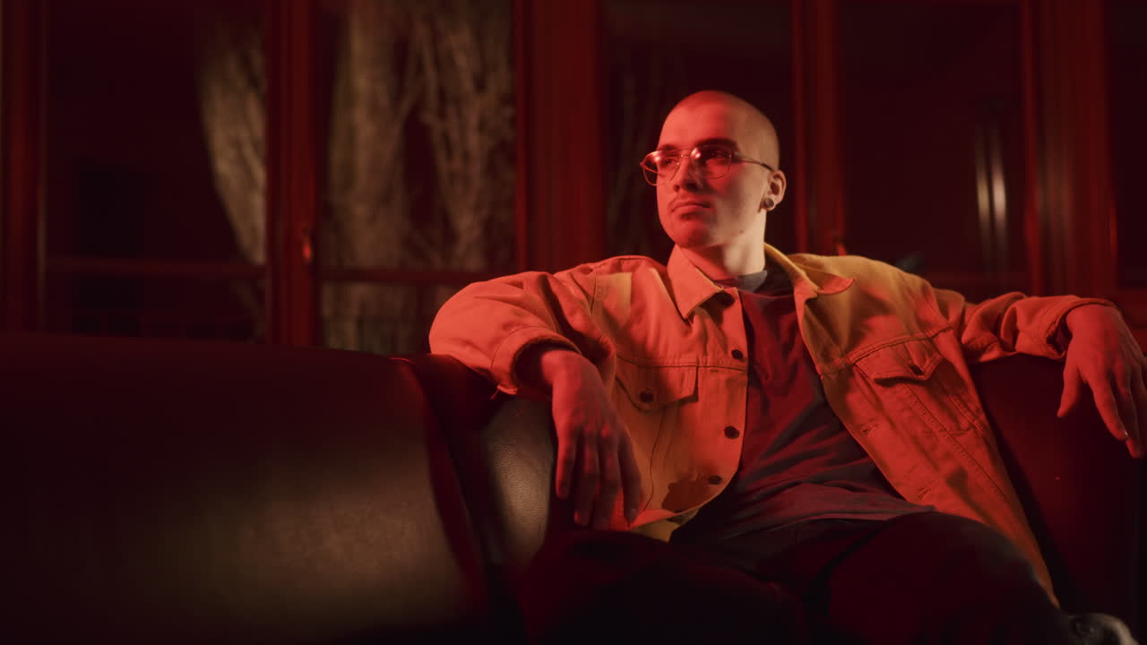 Man Sitting on a Couch in a Red Lit Room